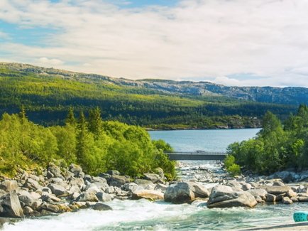 Familie sitzt an einem Fluss mit einem Stausee mit Wasserkraftwerk zur Stromerzeugung im Hintergrund