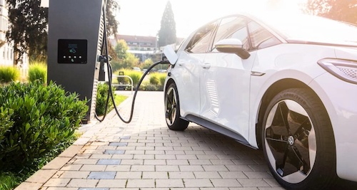 Man sieht ein E-Auto in einer Hausauffahrt, das geladen wird