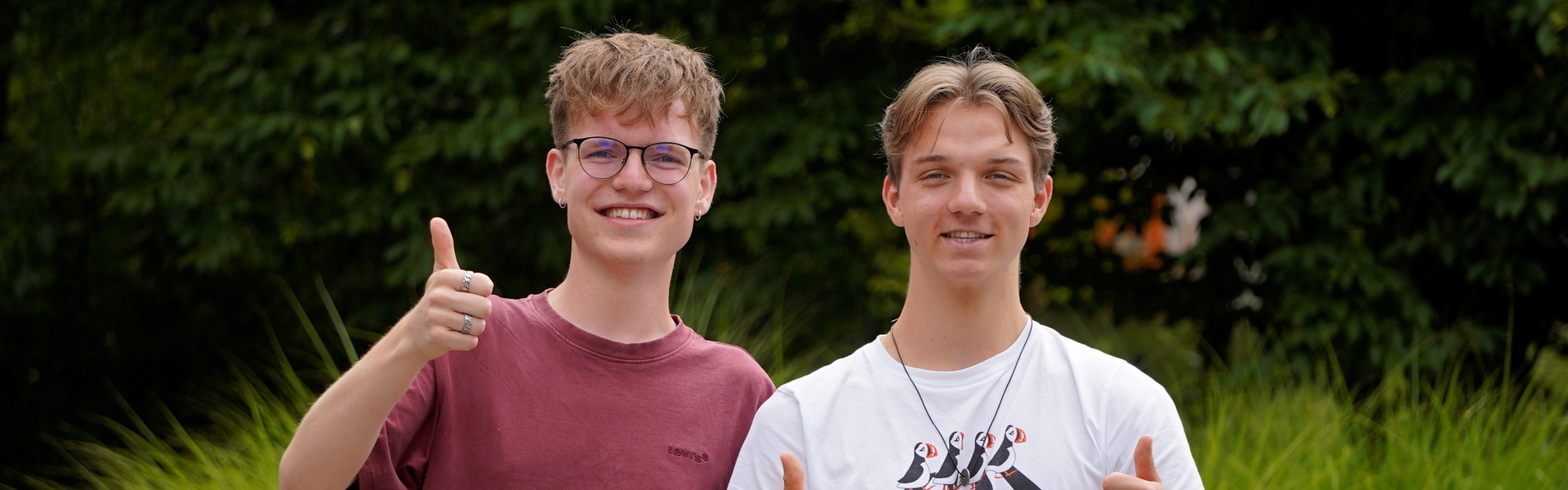 Zwei junge Menschen, die ihr FÖJ bei der Erdgas Südwest absolvieren, stehen auf dem Gelände der Erdgas Südwest und strecken ihre Daumen zustimmend in die Höhe