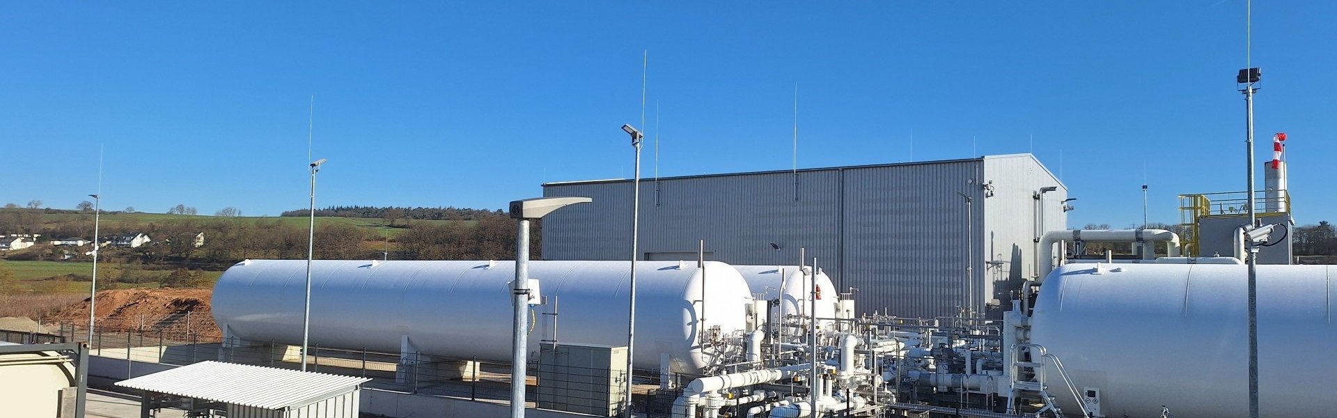 Erdgas Südwest Bio-LNG-Verflüssigungsanlage mit großen Tanks, Rohrleitungen und Industriegebäude unter blauem Himmel.