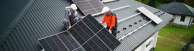 Solarteure installieren eine Solaranlage auf dem Dach eines Einfamilienhauses.