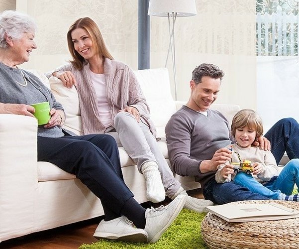 Familie sitzt zufrieden und bestens versorgt im warmen Wohnzimmer zusammen mit der Großmutter.