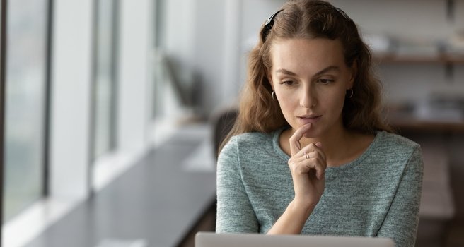 Junge Frau arbeitet konzentriert am Laptop und recherchiert digitale Lösungen.
