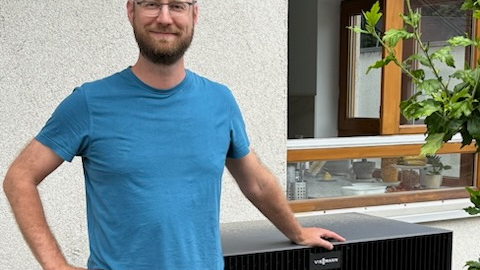 Ein zufriedener Besitzer einer neuen Wärmepumpe aus Karlsruhe vor seinem Wärmepumpen-Außengerät stehend.