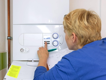 Zu sehen ist eine Gasetagenheizung, an der ein Techniker gerade Einstellungen vornimmt.