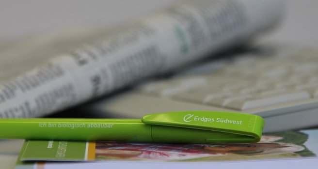 grüner, biologisch abbaubarer Kugelschreiber der Erdgas Südwest vor einer Zeitung