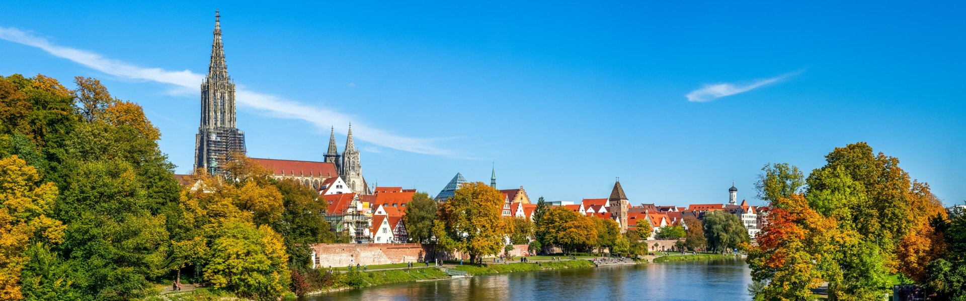 Stadtbild von Ulm mit Blick über die Donau auf das Ulmer Münster und die historische Altstadt bei sonnigem Wetter.
