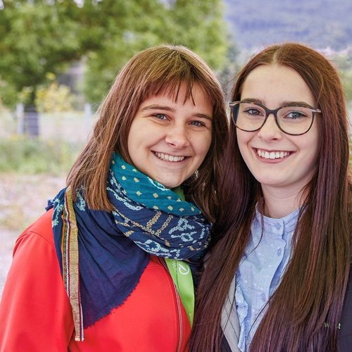 Zwei junge Frauen, die ihr FÖJ bei der Erdgas Südwest absolvieren, stehen vor einer großen Grünfläche