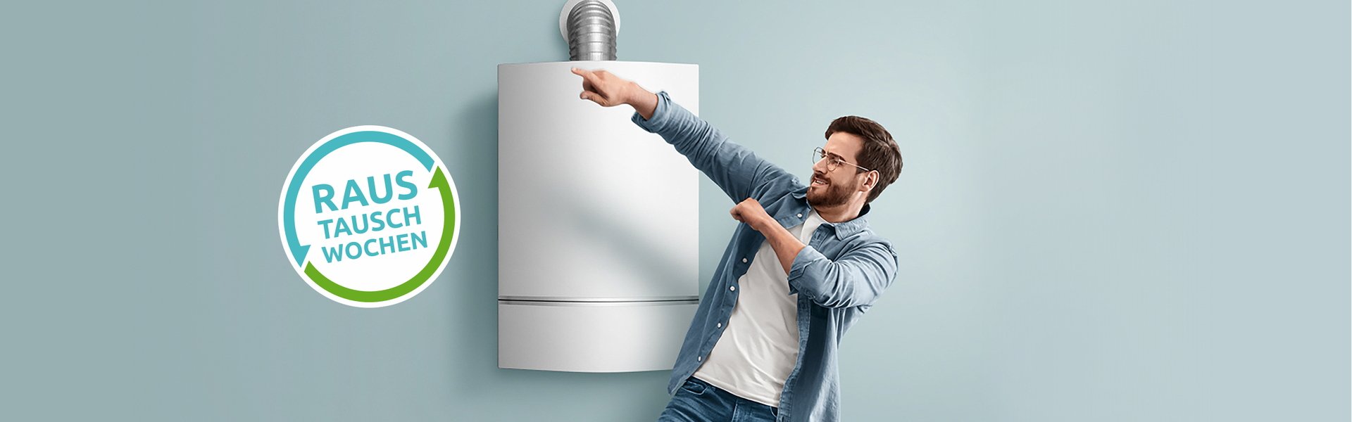 Mann vor Gasheizung der auf das Logo der Raustauschwochen zeigt im breiten Bildformat