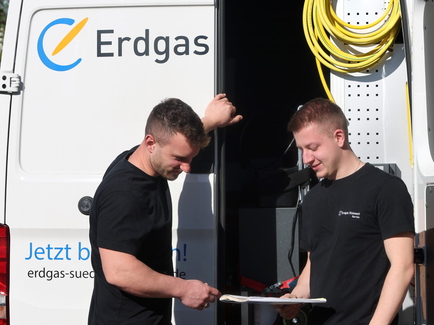 Zwei Heizungsmonteure vor dem Serviceauto stehend im Planungsgespräch zum Einbau der neuen Heizung.