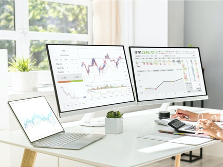 Eine am Schreibtisch sitzende Unternehmensmitarbeiterin beobachtet und kalkuliert die Energie-Börsenpreise.