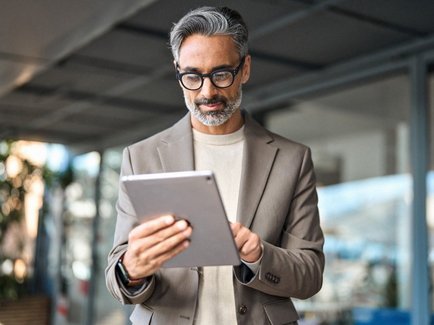 Erfahrener Geschäftsmann nutzt im Büro ein Tablet für Analyse und Beratung.