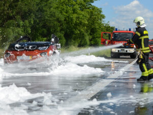 Feuerwehr löscht mit Schaum ein brennendes Elektroauto auf der Autobahn
