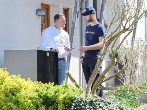 Zwei Männer im Gespräch vor einer Wärmepumpe