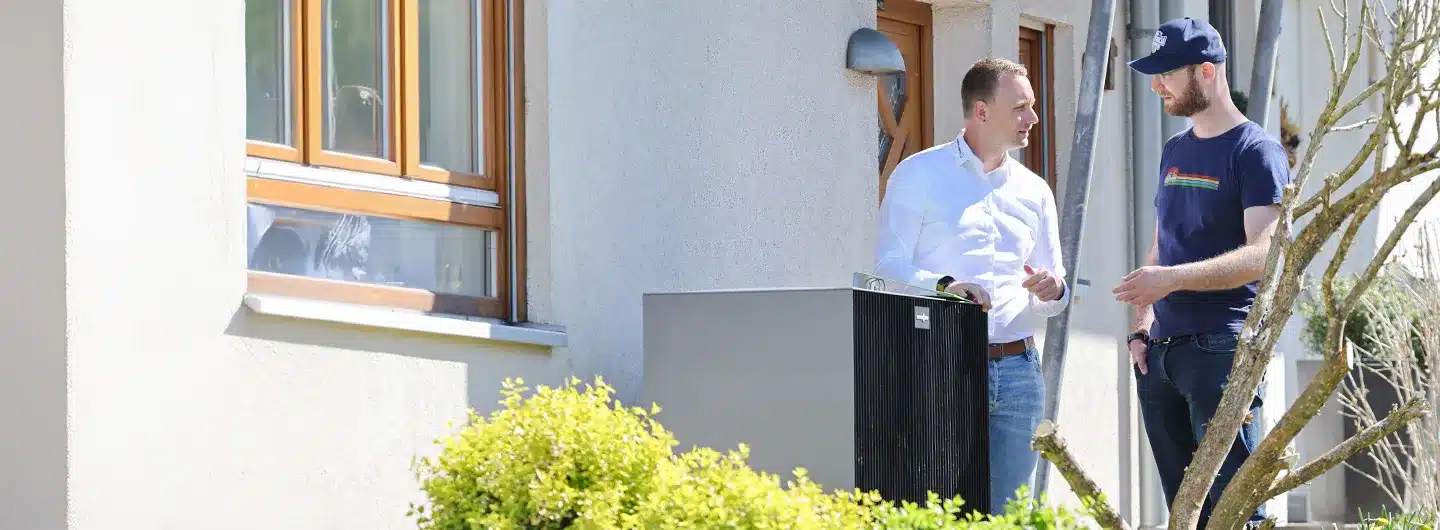 Zwei Männer im Gespräch vor einer Wärmepumpe