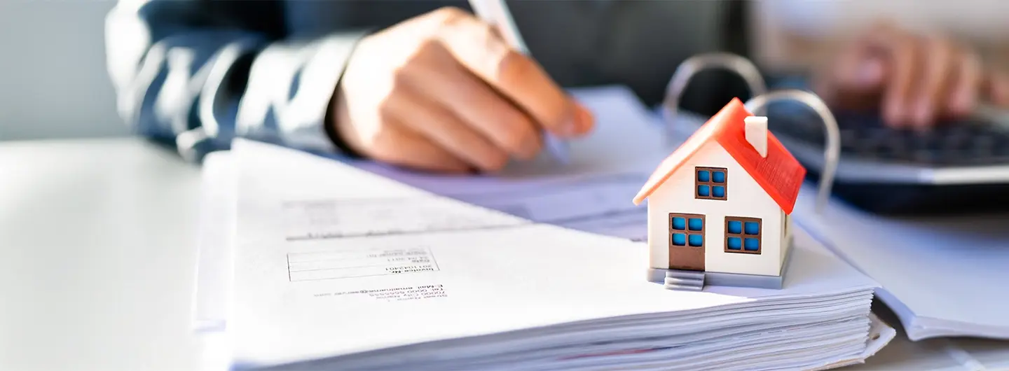 Ein Energieberater arbeitet an Papierunterlagen, auf denen ein kleines Haus steht