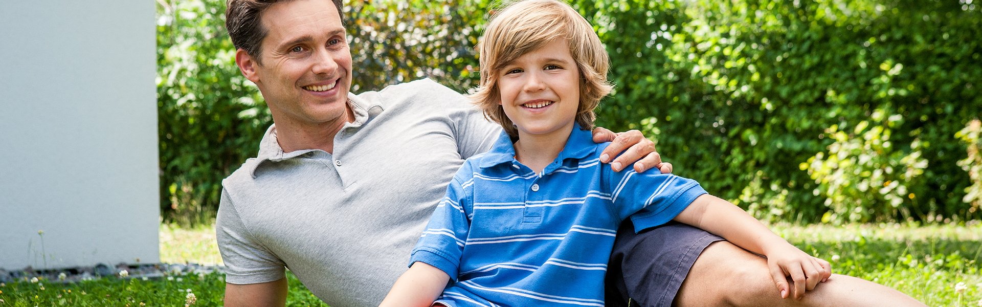 Vater und Sohn sitzen im Garten auf dem Rasen